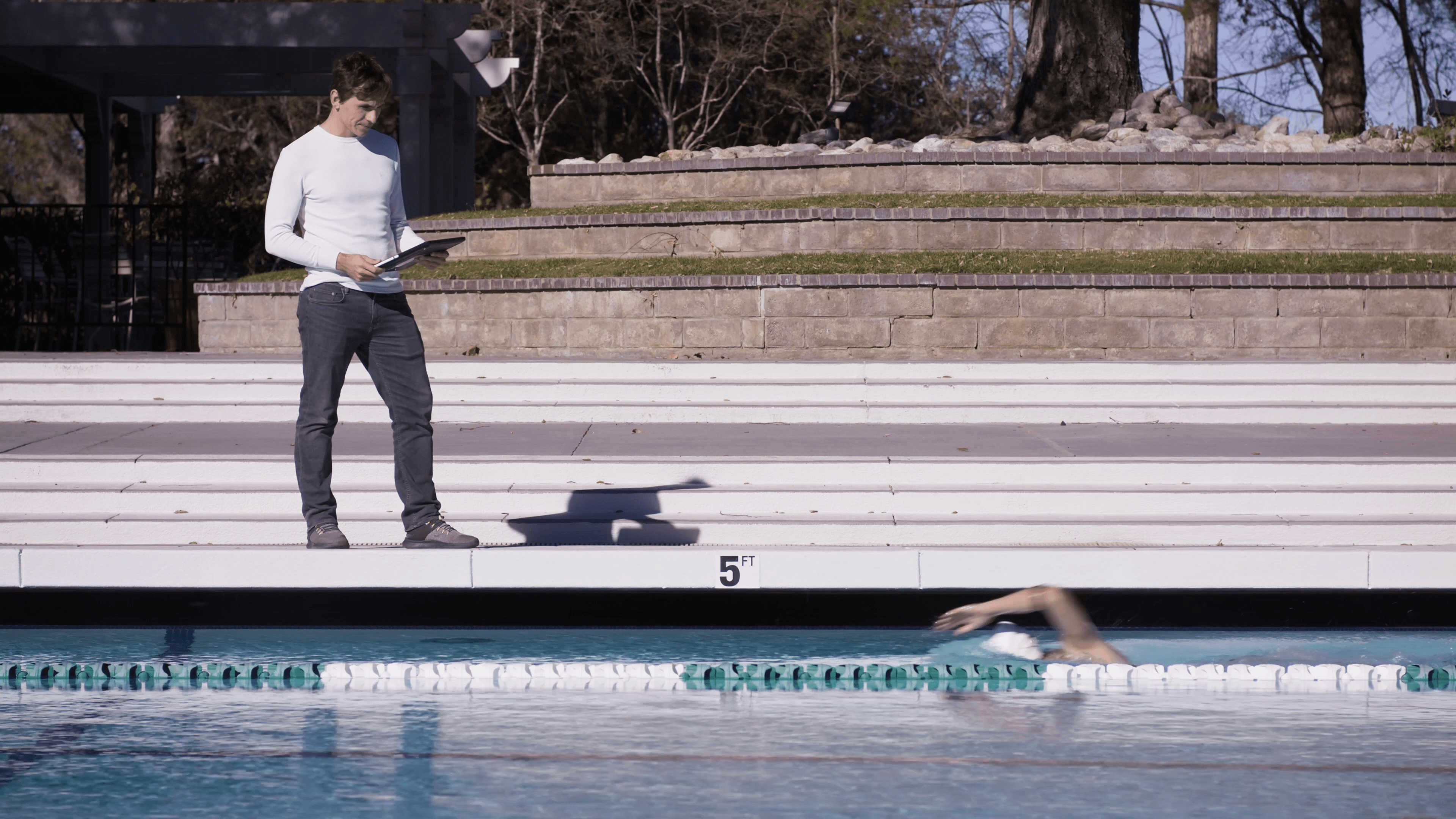 Coach Konrad on pool deck watching a swimmer with Morphwear sensor